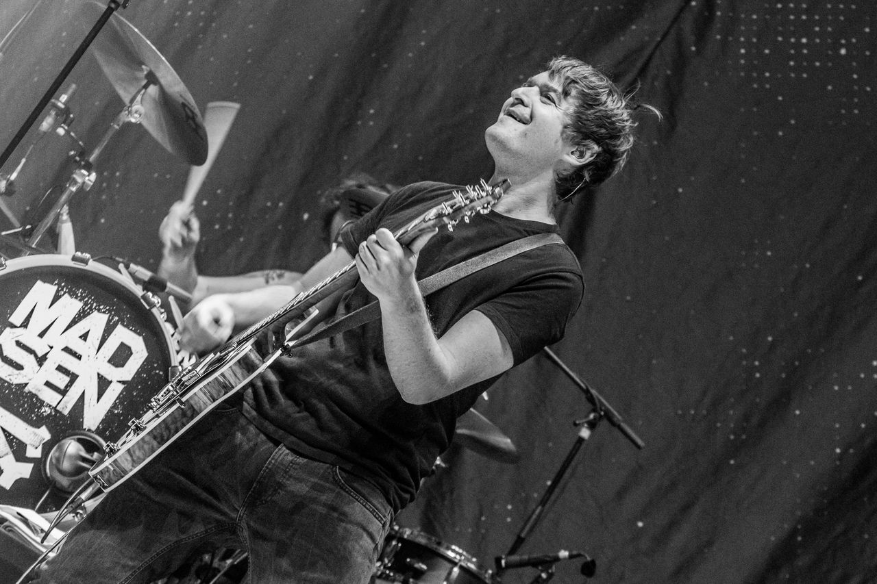 Schwarz-weiß: Madsen-Gitarrist legt den Kopf in den Nacken, im Hintergrund die Bassdrum mit Band-Logo